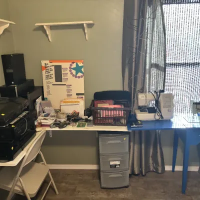 Sale Photo Thumbnail #24: Craft and office workspace featuring audio electronics stacked on wall-mounted shelving, a vintage Singer sewing machine on a blue painted table, and various crafting supplies.