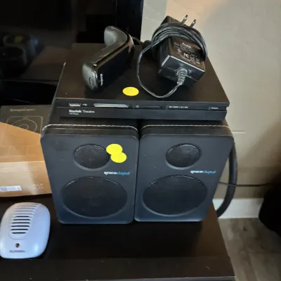 Sale Photo Thumbnail #29: Kodak Theatre HD Player console with remote and power supply, stacked atop a pair of Grace Digital black desktop speakers.