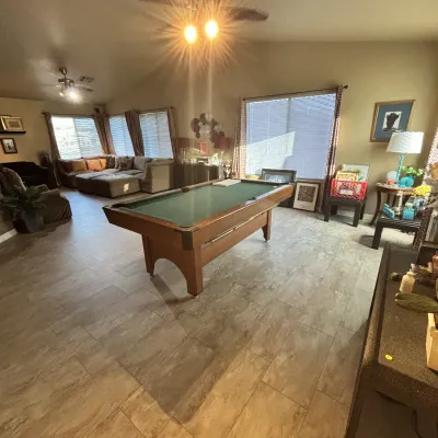 Sale Photo Thumbnail #34: Spacious game room featuring a traditional wood pool table with green felt, surrounded by home furnishings and living room decor.