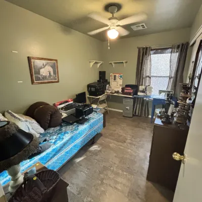 Sale Photo Thumbnail #13: Bedroom filled with various items for sale, including a twin mattress, home office desk with computer equipment, sewing machines, and wooden furniture pieces.
