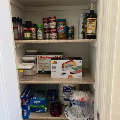 Sale Photo Thumbnail #26: Pantry contents featuring canned goods, condiments, kitchen gadgets including an OXO grate set, storage containers, and paper products.