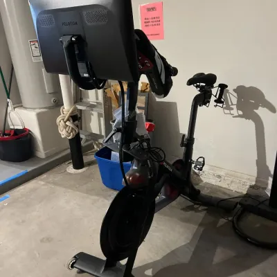 Sale Photo Thumbnail #38: Peloton stationary exercise bike with attached touchscreen monitor, clip-in pedals, and rear weight holders.