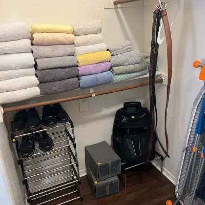 Sale Photo Thumbnail #29: Closet filled with household goods, including neatly folded bath towels, men's shoes on a metal rack, leather belts, and a black backpack.