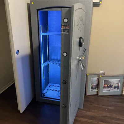 Sale Photo Thumbnail #20: Champion Safe Co. safe featuring a textured gray finish, digital lock keypad, heavy-duty locking bolts, and an illuminated interior with gun racks.