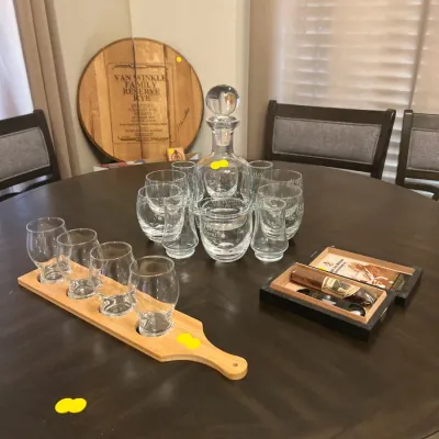 Sale Photo Thumbnail #31: Van Winkle-branded glassware set featuring a decanter, lowball glasses, and a tasting flight board with Glencairn glasses alongside a wooden barrel head sign.