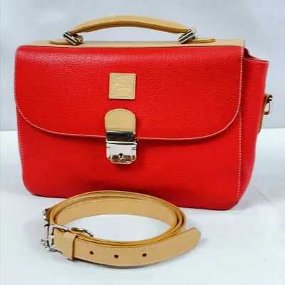Dooney & Bourke red pebbled leather satchel bag featuring tan leather trim, top handle, silver-tone lock hardware, and a detachable...