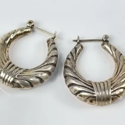 Pair of vintage sterling silver ribbed creole hoop earrings with latch-back closures, showing light surface tarnish.