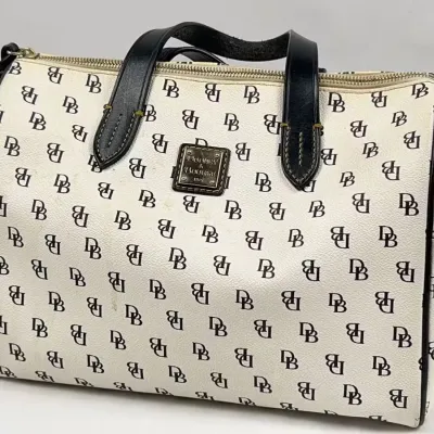 Dooney & Bourke DB monogram coated canvas satchel handbag with black leather handles and trim, showing light surface wear.