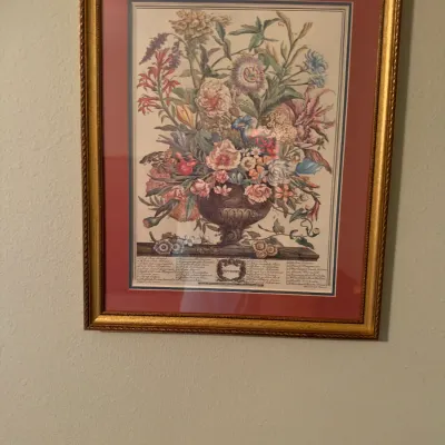 Framed botanical floral print depicting a September arrangement, presented in a pink mat and ornate gold-tone wooden frame.