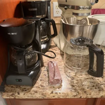 Collection of small kitchen appliances including an cream-colored KitchenAid stand mixer, a Mr. Coffee maker, and a Black & Decker...