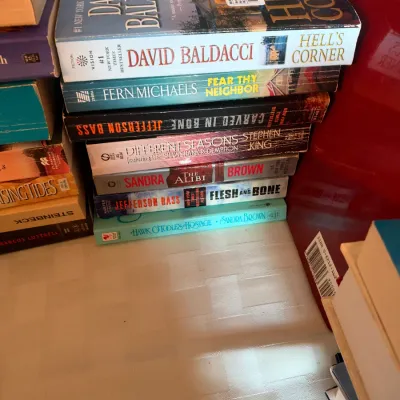Stack of mass-market paperback mystery and thriller novels, including titles by David Baldacci, Stephen King, and Sandra Brown.