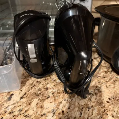 Pair of modern black electric hand mixers, including a Hamilton Beach brand model, resting on a granite countertop.