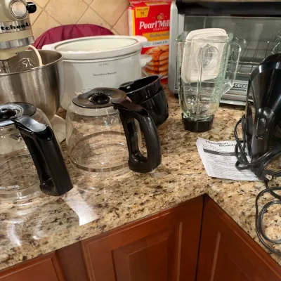 Collection of small kitchen appliances including a KitchenAid stand mixer, Hamilton Beach slow cooker, coffee carafes, blender pitcher,...