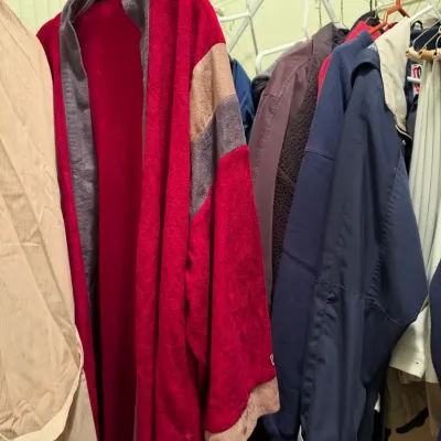 Vintage fleece bathrobe in red, grey, and beige colorblock pattern hanging alongside other outerwear in a closet.