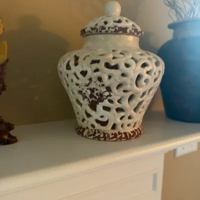 Decorative white glazed reticulated ceramic ginger jar with a lid and rustic distressed brown accents.