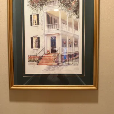 Framed architectural print depicting a Southern plantation-style home with multi-tiered porches, housed under double matting and a gilded...