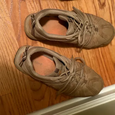 Pair of women's Easy Spirit tan athletic walking shoes with lace-up closures on a hardwood floor.