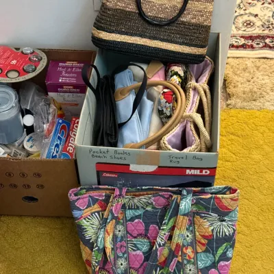 Sale Photo Thumbnail #30: Collection of women's handbags including a Vera Bradley quilted floral tote, a striped woven straw tote, and a cardboard box containing additional purses and toiletries.