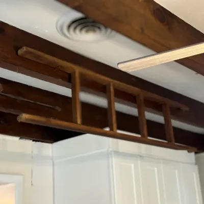 Sale Photo Thumbnail #106: Rustic wooden ladder suspended from ceiling beams, along with a vintage metal oil lantern.