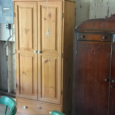 Sale Photo Thumbnail #283: Light knotty pine two-door armoire with bottom drawer next to an antique dark wood cabinet.