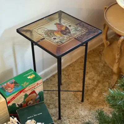 Sale Photo Thumbnail #70: Small metal accent table featuring a glass top with a colorful rooster design.