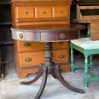 Sale Photo Thumbnail #298: Vintage mahogany drum table with turned pedestal and splayed legs, positioned in front of a light oak dresser.