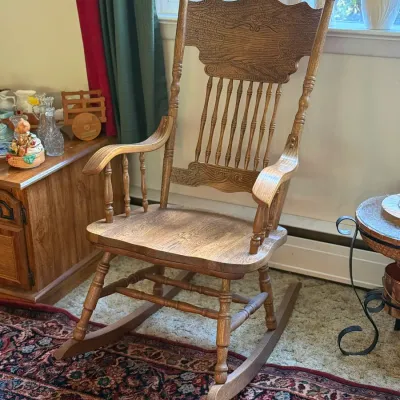 Sale Photo Thumbnail #83: Vintage pressed-back oak rocking chair featuring spindled supports, carved scroll motifs, and turned posts.
