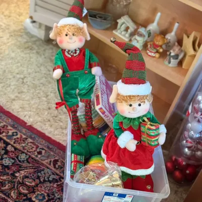 Sale Photo Thumbnail #58: Pair of plush Christmas elf figurines with tall fabric hats displayed inside a plastic storage tub.