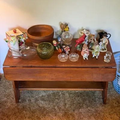 Sale Photo Thumbnail #77: Vintage wooden drop-leaf coffee table displayed with various decor items including porcelain figurines, glass bowls, and a large wooden bowl.