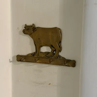 Sale Photo Thumbnail #171: Vintage solid brass cow key holder and wall hook rack featuring four hooks.