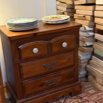 Sale Photo Thumbnail #25: Traditional wooden three-drawer nightstand holding stacks of decorative ceramic plates.