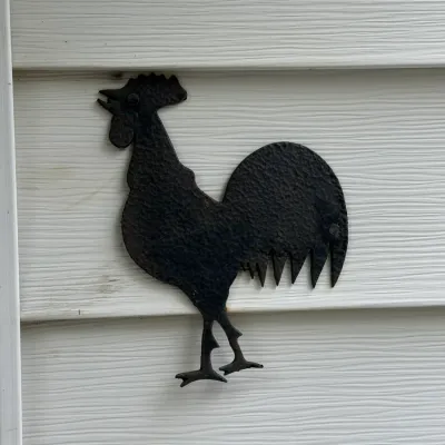 Sale Photo Thumbnail #203: Rustic cast iron or wrought iron rooster wall plaque with a textured finish, mounted on siding.