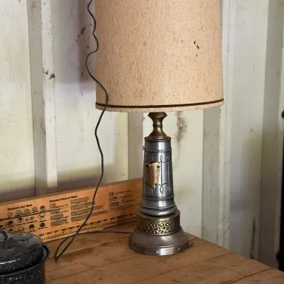 Sale Photo Thumbnail #279: Vintage metal and brass table lamp with a tall cylindrical shade, featuring ornate filigree detailing around the base.