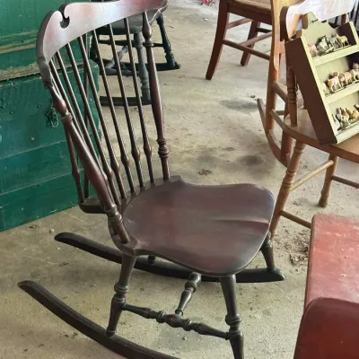 Sale Photo Thumbnail #290: Vintage dark stain wooden spindle-back rocking chair with a contoured seat and turned legs, displayed alongside various rustic furniture pieces.