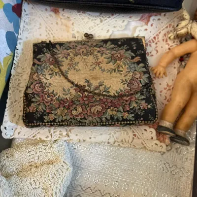 Sale Photo Thumbnail #32: Vintage tapestry floral handbag with a chain strap resting on lace alongside other vintage accessories.