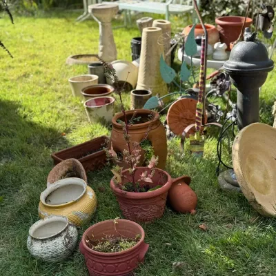 Sale Photo Thumbnail #252: Collection of outdoor garden decor including terracotta planters, ceramic pots, concrete birdbaths, metal garden stakes, and a light blue metal bench.
