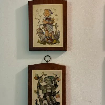 Sale Photo Thumbnail #49: Pair of vintage Hummel wood-mounted wall plaques featuring illustrations of children, each fitted with a top brass hanging ring.