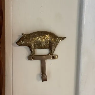 Sale Photo Thumbnail #103: Vintage brass pig-shaped wall hook, mounted with screws to a door or wall frame.