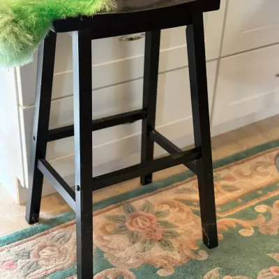 Sale Photo Thumbnail #137: Black wooden backless bar stool with square legs, supporting a green feather duster and small fishing rod.