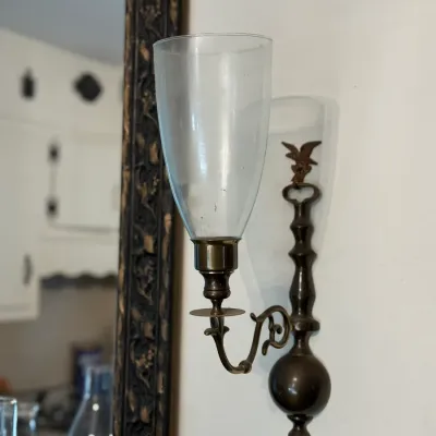 Sale Photo Thumbnail #164: Vintage brass wall sconce with a clear glass hurricane shade and a small eagle accent.