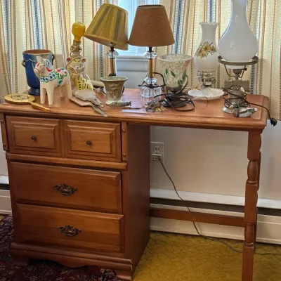 Sale Photo Thumbnail #35: Vintage wooden desk topped with an array of home decor items, including small lamps, milk glass hurricane lamps, and a Swedish Dala horse figurine.