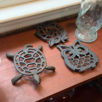 Sale Photo Thumbnail #191: Set of three vintage cast iron decorative trivets, including a turtle and owl motif, displaying light patina and age-appropriate wear.