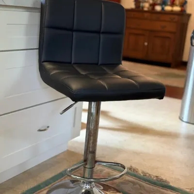 Sale Photo Thumbnail #138: Modern adjustable bar stool featuring a tufted black faux leather seat, chrome pedestal base, footrest, and hydraulic lever.