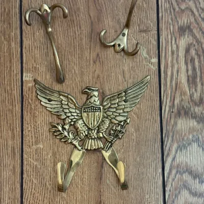 Sale Photo Thumbnail #183: Set of vintage brass hardware hooks, including a large Federal-style American eagle coat hook and two matching classical scroll-style wall hooks.