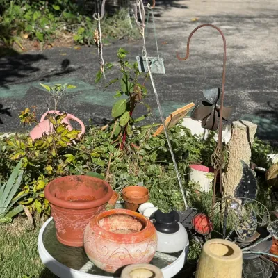 Sale Photo Thumbnail #243: Collection of outdoor garden decor and planter pots, including terracotta planters, shepherd's hooks, and decorative lawn ornaments.