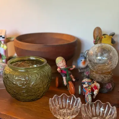 Sale Photo Thumbnail #79: Collection of tabletop decor including an olive green textured glass bowl, a wooden serving bowl, small clear glass dishes, and vintage-style figurines.