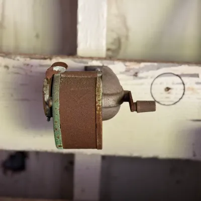 Sale Photo Thumbnail #258: Vintage hand-crank wall-mounted pencil sharpener with significant surface rust and patina.