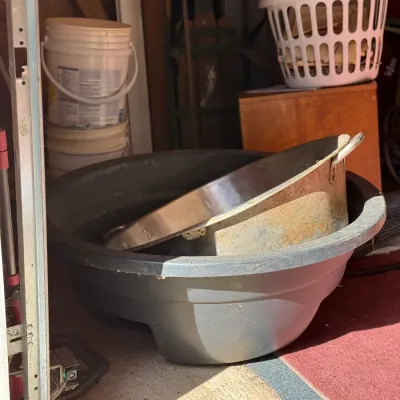 Sale Photo Thumbnail #237: Large vintage metal cazo pan resting inside a heavy-duty grey plastic wash basin in a garage setting.