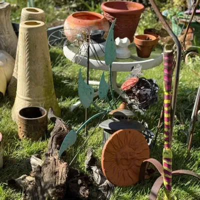 Sale Photo Thumbnail #249: Collection of outdoor garden decor and planter pots, featuring a terra cotta sun face plaque, decorative garden stakes, and various ceramic vessels.