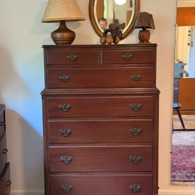 Sale Photo Thumbnail #44: Traditional mahogany chest on chest dresser with ornate metal bale handles, accompanied by various table lamps and decor atop the piece.